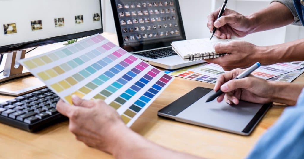 Dizajneri upoređuju uzorke boja pored laptopa i grafičkog tableta