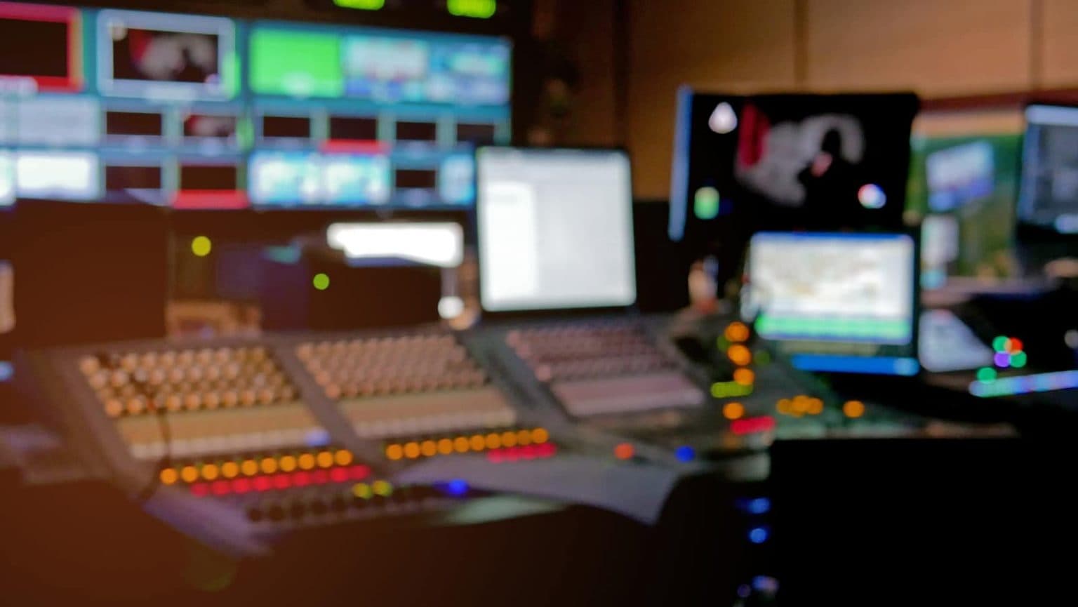 Broadcast control room with a vision mixing desk and a wall of monitors